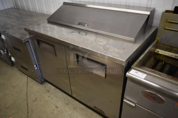 Stainless steel commercial prep table with two doors, refrigerated section, and top lid. Used condition with minor wear.
