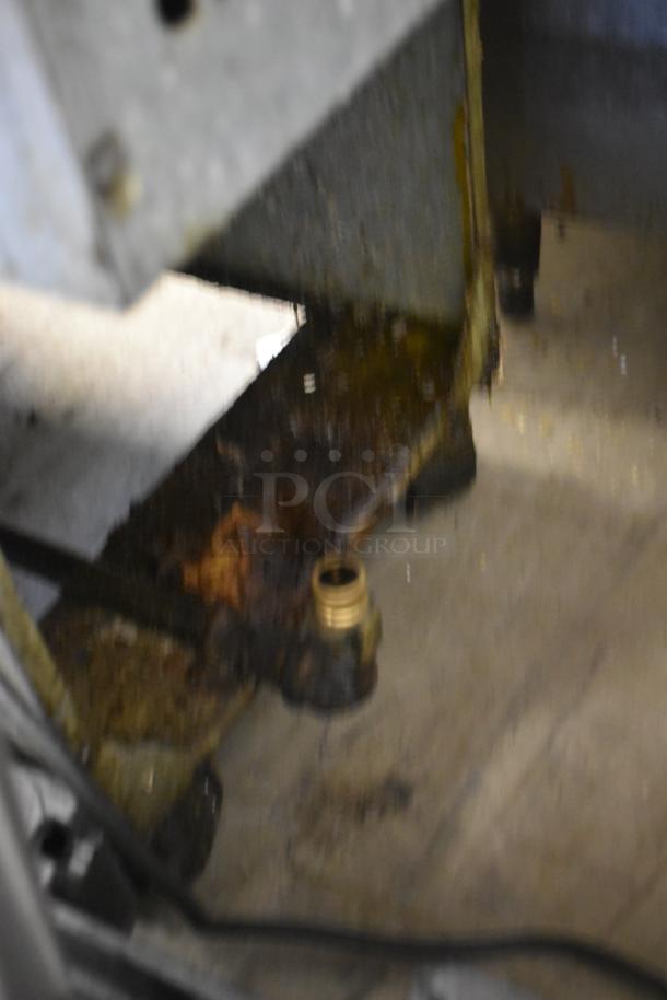Blurred industrial machinery base, showing rust and brass fitting. Condition indicates significant wear.