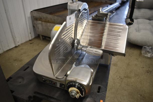 Commercial meat slicer with adjustable thickness dial, stainless steel blade and guard, in used condition. Auction tag: 95.