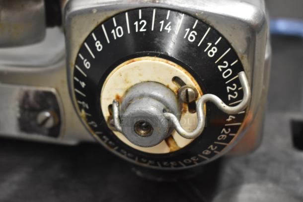 Close-up of vintage mechanical device knob with numbered dial, showing wear and rust, indicating age and use.