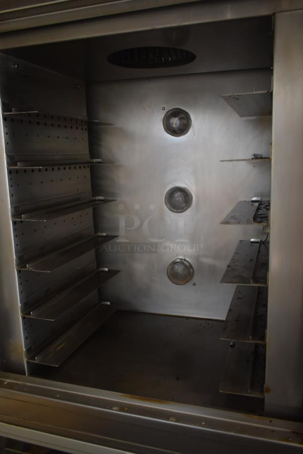 Commercial-grade stainless steel convection oven interior, featuring multiple shelves and a vented back panel in used condition.