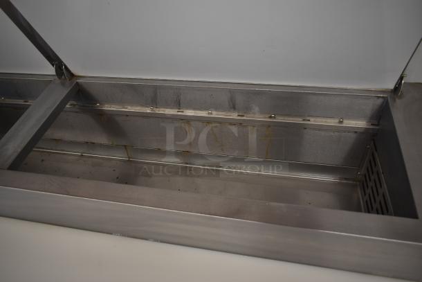 Stainless steel commercial-grade freezer chest, showing interior with visible rust stains and signs of wear.