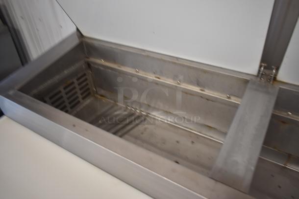 Stainless steel commercial ice bin, used, with hinged lid and interior drainage, showing signs of wear.