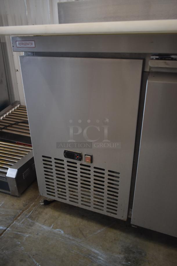 Stainless steel commercial refrigerator with "Refrigerator" label. Features vented front panel, temperature gauge. Good condition.