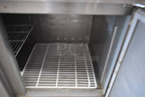 Metal commercial refrigerator interior with wire shelves, showing signs of use. No visible labels or markings.