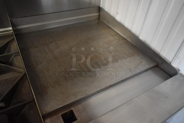 Commercial stainless steel griddle with slight surface wear, featuring smooth cooking surface and raised edges for easy cleaning.