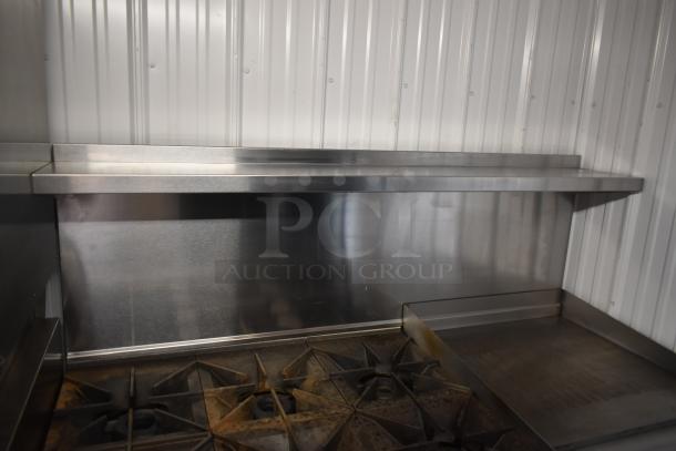 Stainless steel commercial kitchen cooktop with multiple burners, griddle, and backsplash, in good condition.