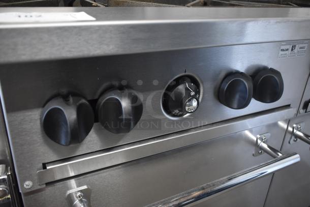 Stainless steel commercial stove with five black control knobs, thermostat dial with temperature markings, and Vulcan branding.