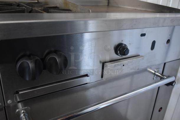 Commercial stainless steel oven with multiple burners, control knobs, and a metal handle. Good condition.