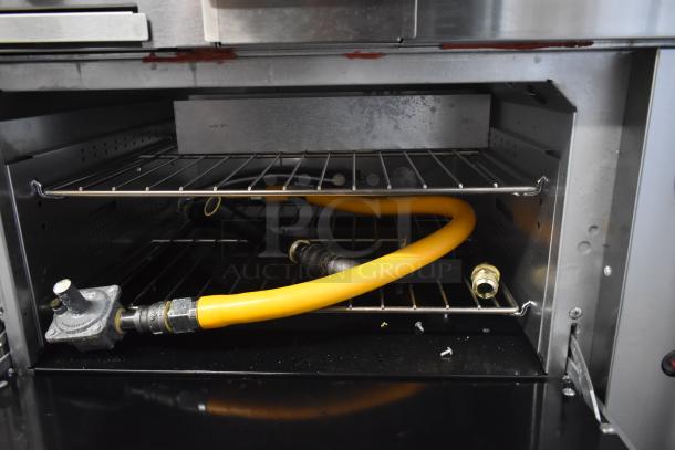 Commercial oven interior showing stainless steel racks and a yellow gas line with a regulator. Appears in used condition.