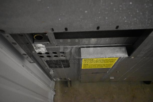 Industrial metal equipment panel with visible ducts and a yellow notice label for operational guidelines. Condition shows wear.