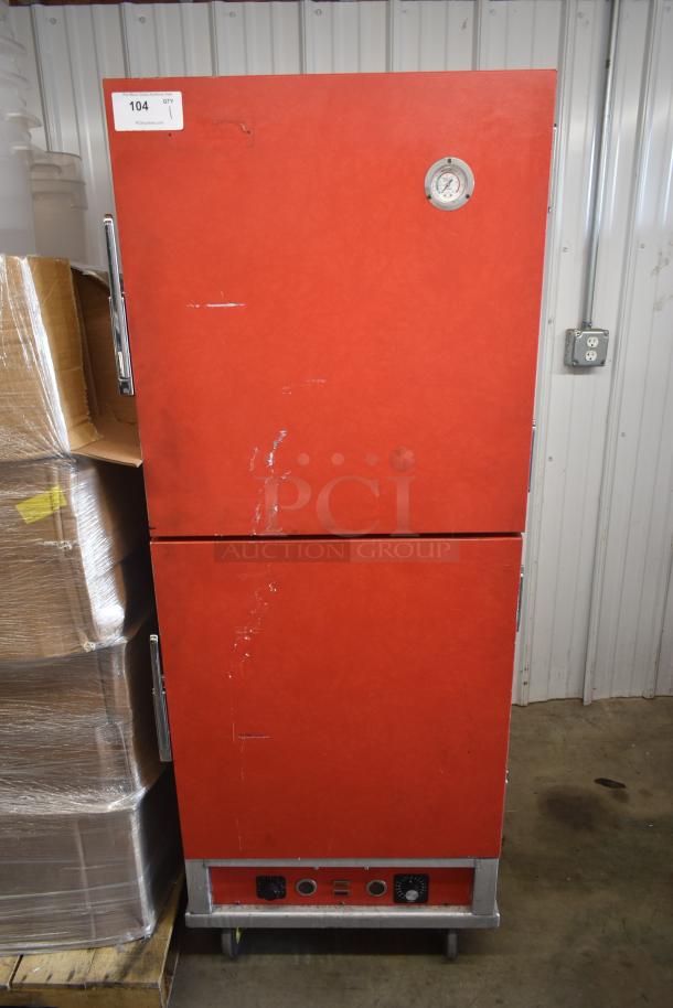 Red double-door commercial warmer with temperature gauge, likely for food service. Shows signs of wear. Auction tag "104".