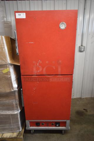 Red double-door commercial warmer with temperature gauge, likely for food service. Shows signs of wear. Auction tag "104".
