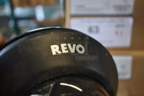 Close-up of a black camera lens with "REVO" branding, showing slight wear. Suitable for videography, emphasizing lens quality.