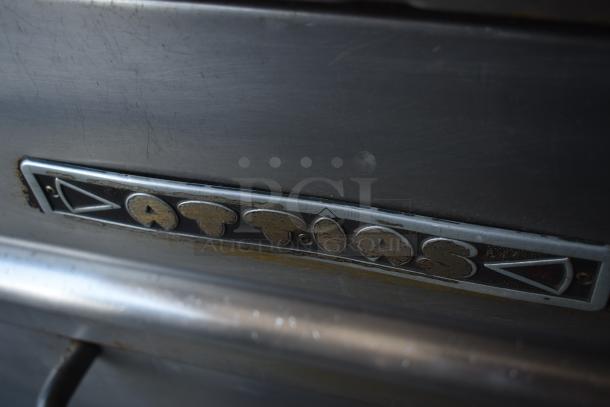 Vintage metal appliance with "Attias" label, showing wear and rust, indicating age and use.