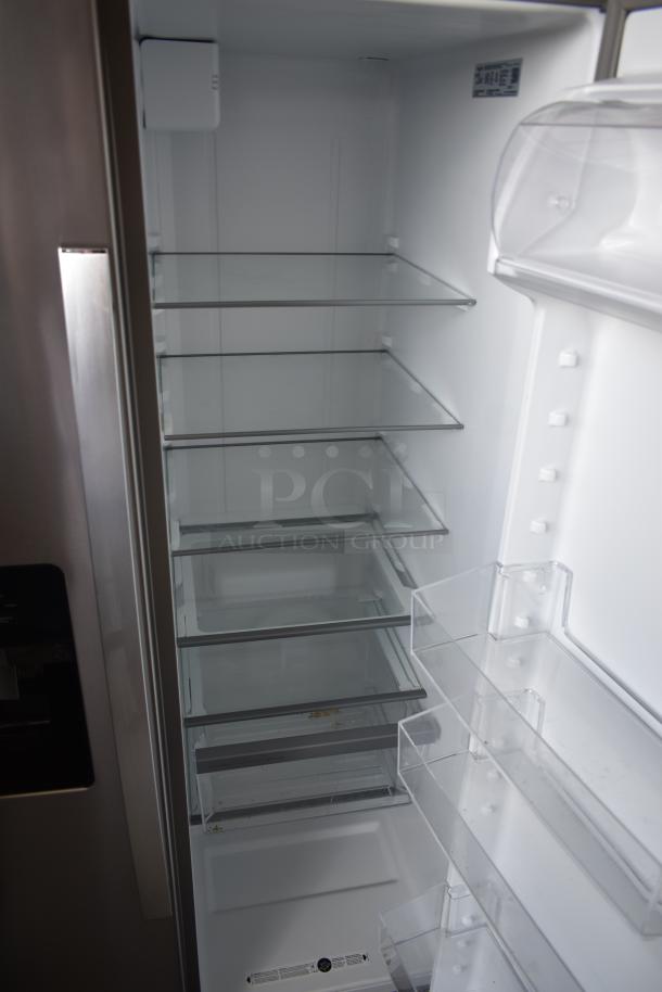 Stainless steel refrigerator, interior view, six glass shelves, three door trays, clean condition, visible model label.