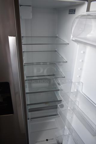 Stainless steel refrigerator, interior view, six glass shelves, three door trays, clean condition, visible model label.