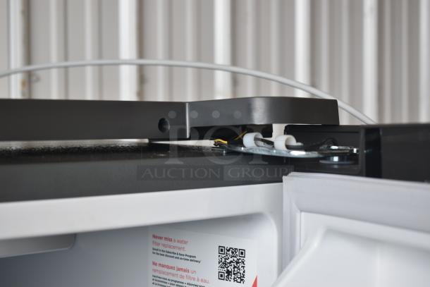 Refrigerator door hinge with wiring visible, showing QR code sticker for filter replacement subscription.
