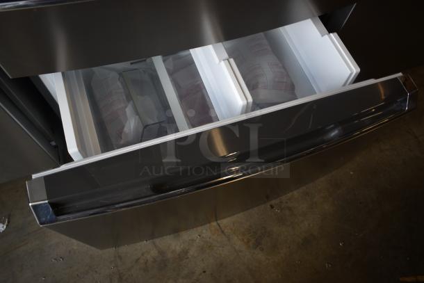 Stainless steel refrigerator drawer with white plastic compartments and visible instruction labels, in excellent condition.