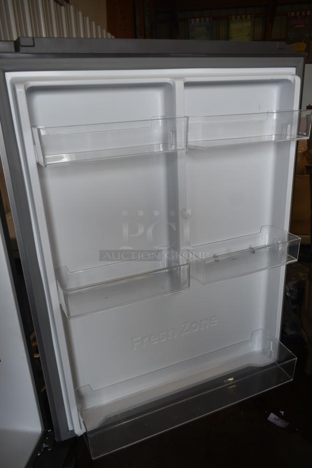 Open refrigerator door with clear plastic shelves, labeled "Fresh Zone," in excellent condition.