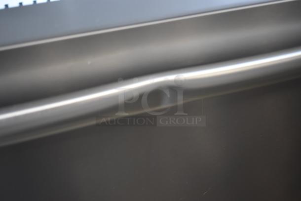 Close-up of a dark metallic panel with a dented surface, indicating possible damage. No visible tags or labels.