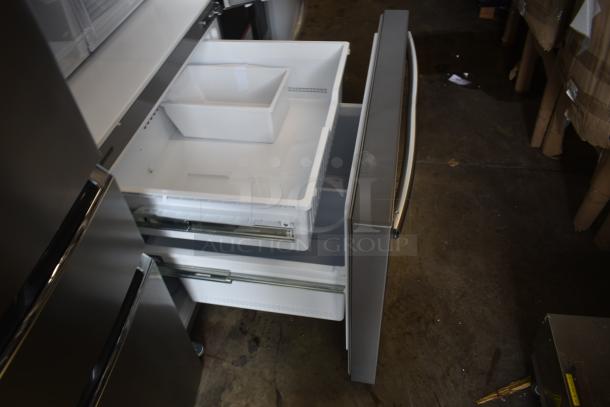 Stainless steel bottom-freezer refrigerator, open drawers, visible storage bins, excellent condition.