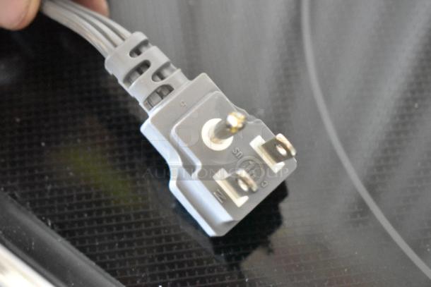 Gray electrical plug with three prongs; features markings "N," "L," and "US," indicating live and neutral connections.