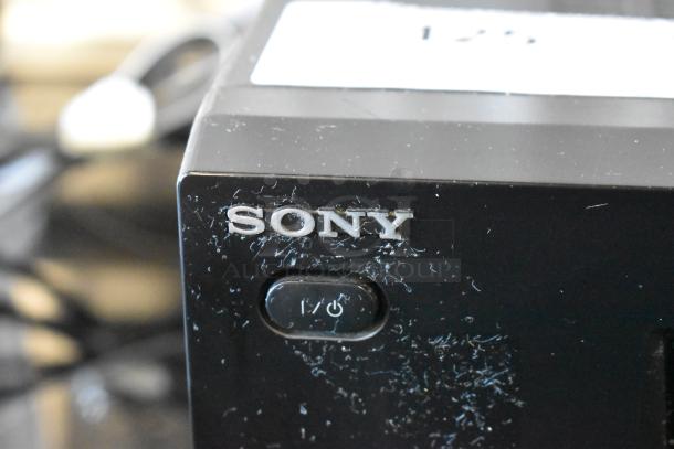 Sony electronic device with visible power button. Scratches on black surface indicate moderate wear.