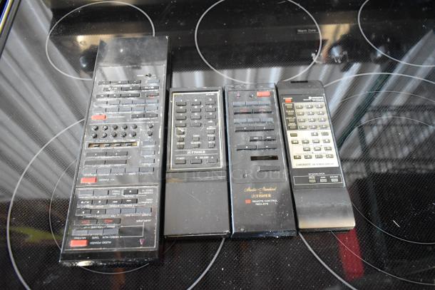 Four vintage remote controls, including Fisher and Hitachi models, showing signs of wear and various button features.
