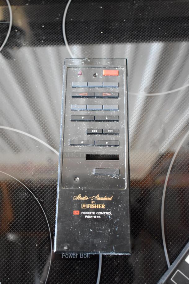 Fisher REM-875 remote control, vintage condition, black with multiple buttons, "Studio-Standard by Fisher" label visible.