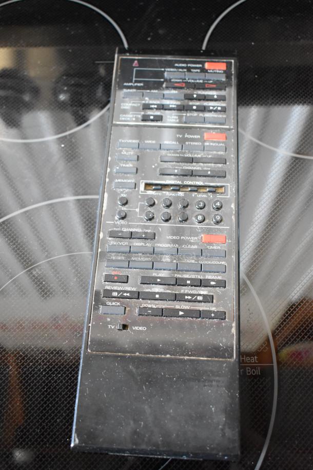 Vintage multi-function remote control with numerous buttons, slightly worn condition, labels indicate audio, video, and TV functions.