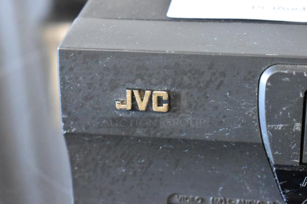 Close-up of a vintage JVC electronic device with a gold logo. Surface shows signs of wear.