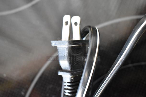 Close-up of a black power cord with a two-prong plug, showing slight wear. Cord is coiled and intact.