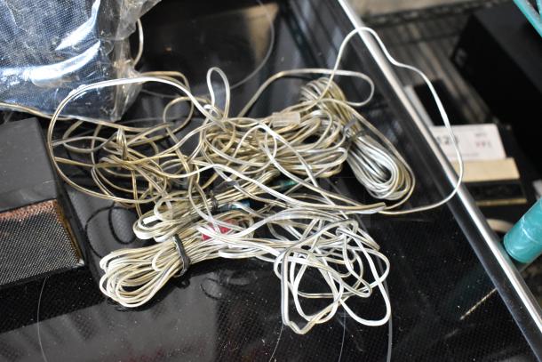 Tangled bundle of clear speaker wires, various lengths, used condition, resting on a dark surface.