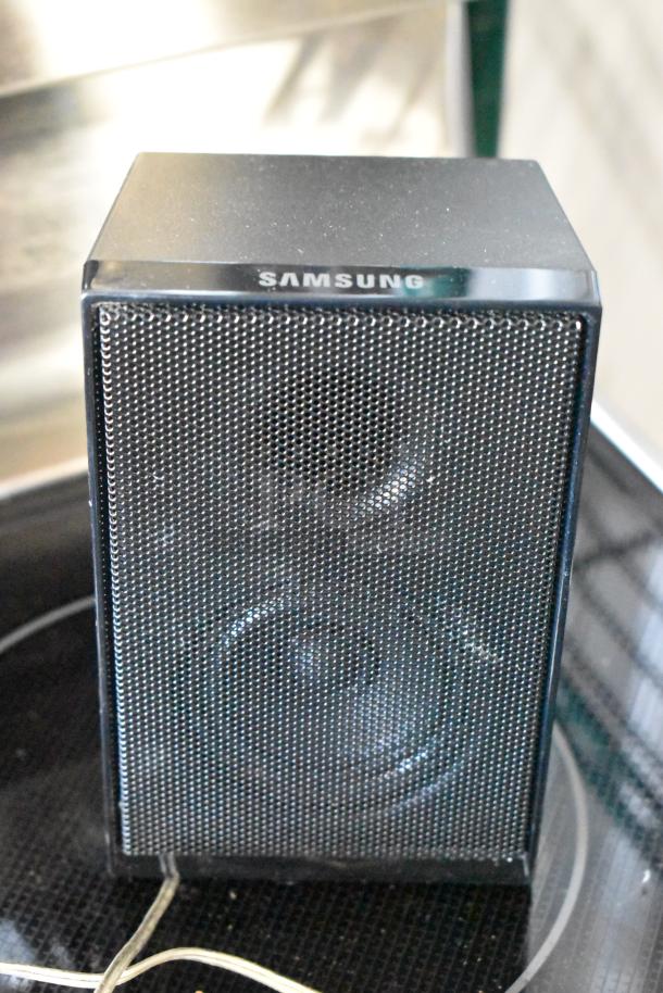 Samsung bookshelf speaker with black mesh grille, visible branding on top. Appears in good condition with some dust.