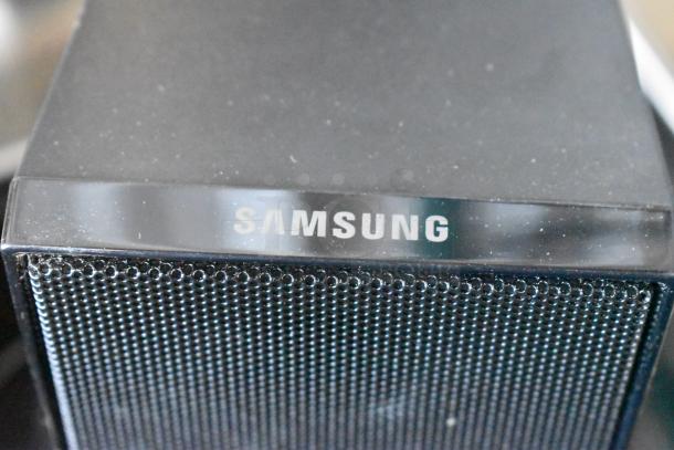Samsung black speaker, used condition, features mesh grille and logo on top. Dust visible on surface.