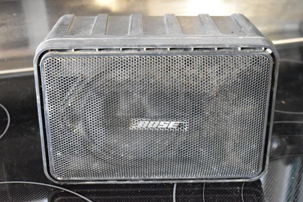 Vintage Bose speaker with black metal grille, showing wear. Embossed Bose logo, model and specs unclear. Suitable for collectors.
