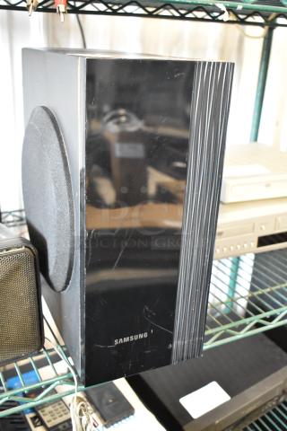 Samsung black speaker, rectangular with side panel speaker and minor scratches. Brand name visible at bottom.