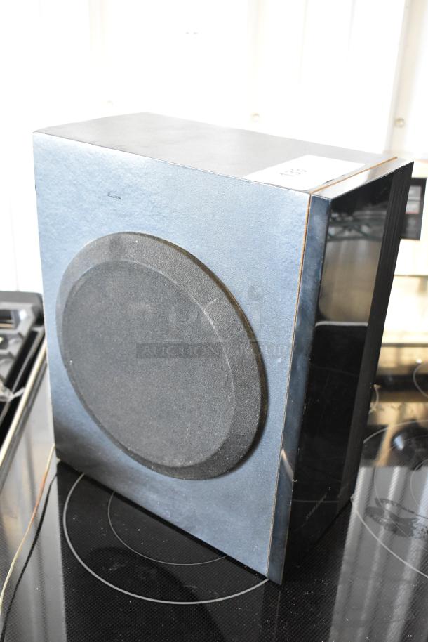 Black subwoofer speaker with circular grille, in good condition. Number label "103" on top. Suitable for audio systems.