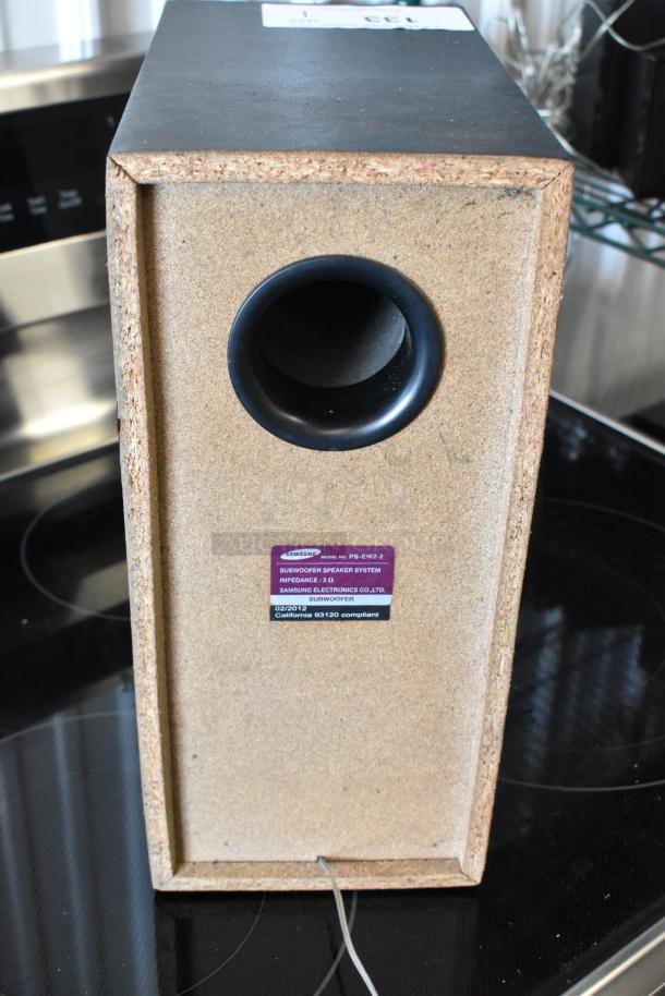 Samsung subwoofer model PS-EW2-2, beige wood finish, rear port design. Label indicates 3Ω impedance, compliant with California 93120.