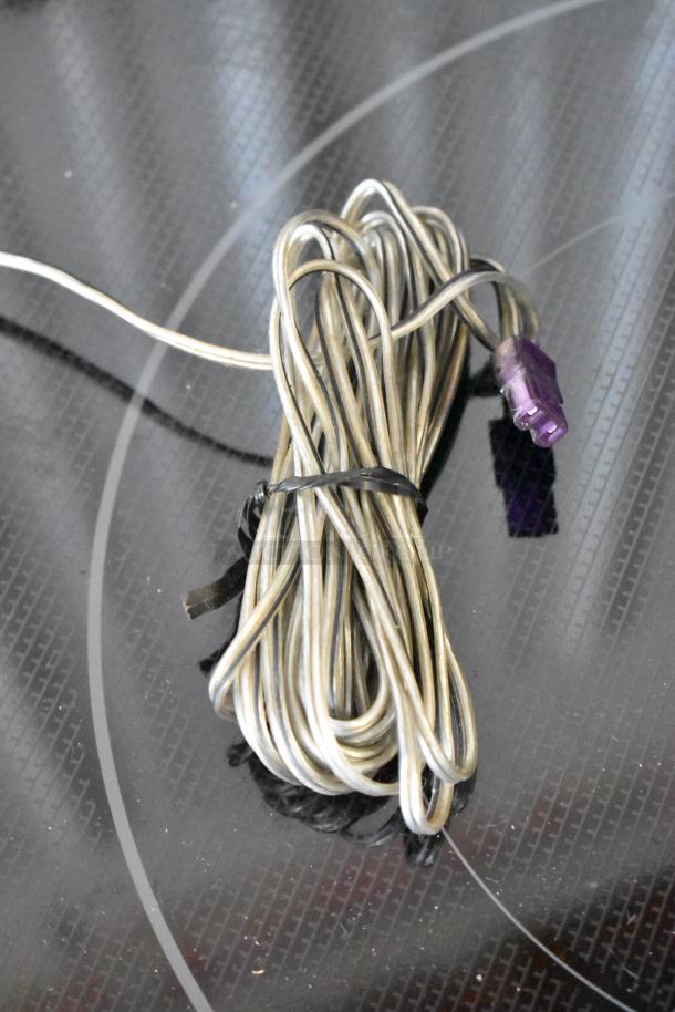 Coiled speaker wire with purple connector, good condition, securely tied with black twist tie.