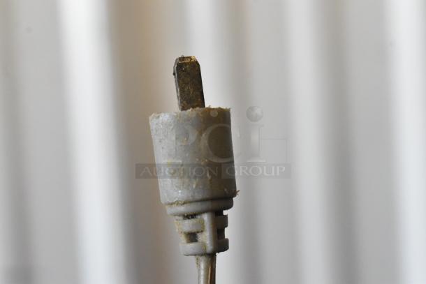 Close-up of a vintage, worn electrical plug with a rusty prong and frayed insulating cover.