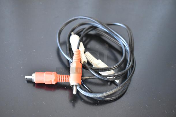 Black RCA audio cable with red and white connectors, coiled on a dark surface. Visible wear, functional condition.