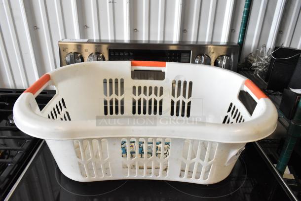 White plastic laundry basket with red handles, open grid design, showing signs of wear. Visible label with product details.