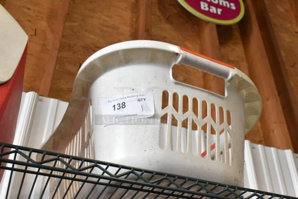 Plastic laundry basket with handles, slightly worn, auction tag "138" indicating quantity 1, PCI Auctions label visible.