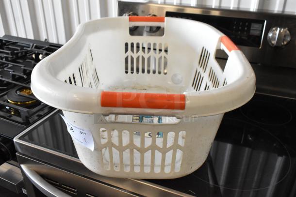 White plastic laundry basket with red handles, showing signs of wear. Auction tag attached.