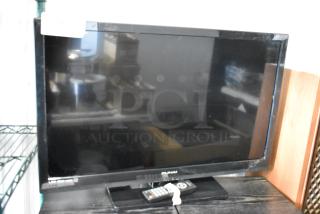 Flat-screen Sylvania TV with remote, reflective screen, mild wear on edges. Auction tag visible, suggesting item number.