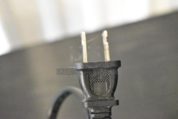 Two-prong power cord plug with a black textured grip, showing minor wear.
