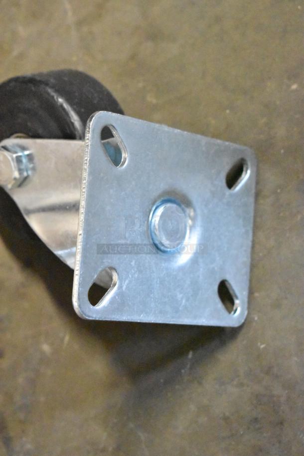 Metal swivel caster with black rubber wheel, four mounting holes, and central pivot, in good condition.