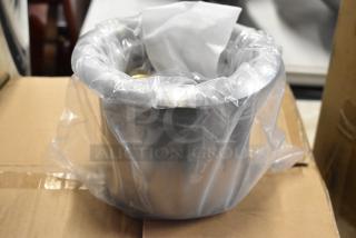 Stainless steel container wrapped in clear plastic, showing protective packaging, on a cardboard surface.